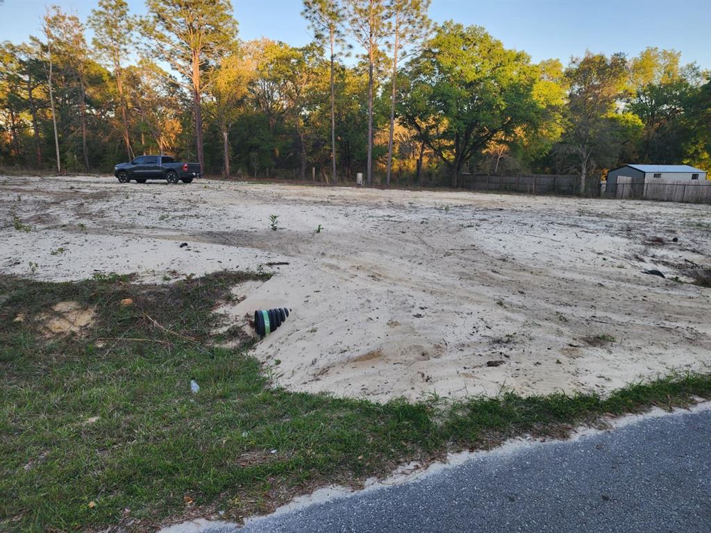 A cleared, sandy vacant lot features a drainage pipe and a parked truck in back — SW 110TH COURT, DUNNELLON, FL