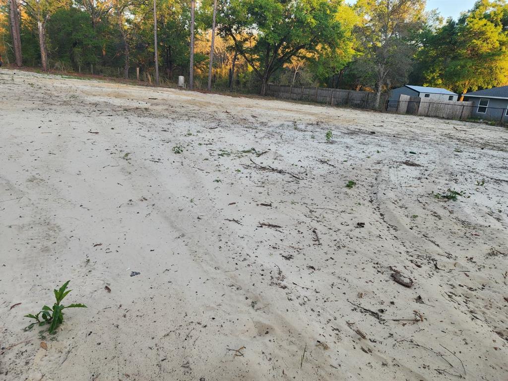 A large, cleared, sandy residential lot with scattered debris and surrounding trees — SW 110TH COURT, DUNNELLON, FL