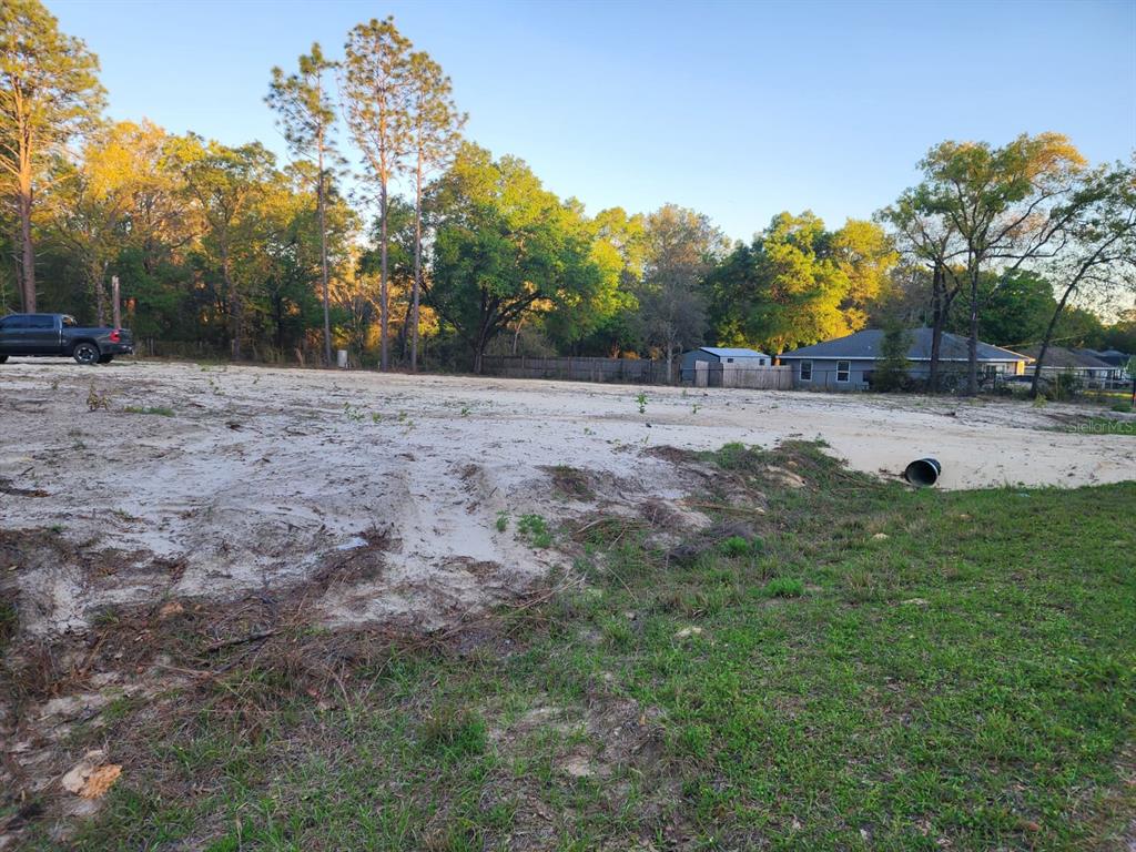 A cleared, sandy residential lot with a truck parked in the background near trees — SW 110TH COURT, DUNNELLON, FL