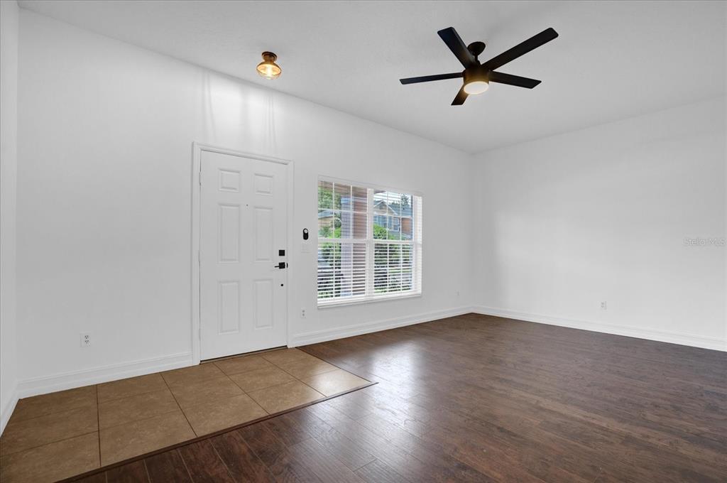 An entryway with tile flooring, a white front door, and a living area with wood-look floors — 16130 OLD ASH LOOP, ORLANDO, FL