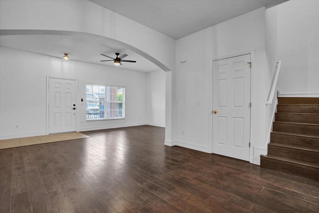 An interior view shows a living area with wood flooring, an arched entryway, and stairs — 16130 OLD ASH LOOP, ORLANDO, FL