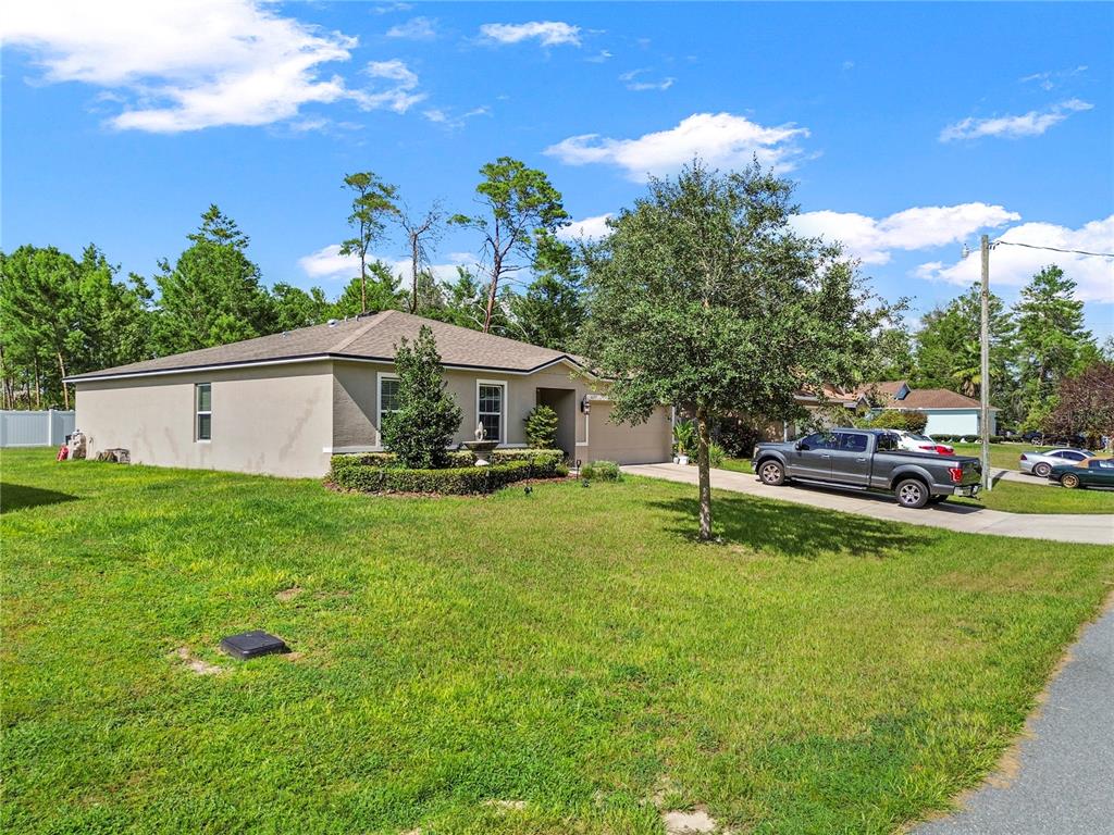A single-story house with a tan exterior, a driveway, and a large front yard — 3697 SW 128TH PLACE, OCALA, FL