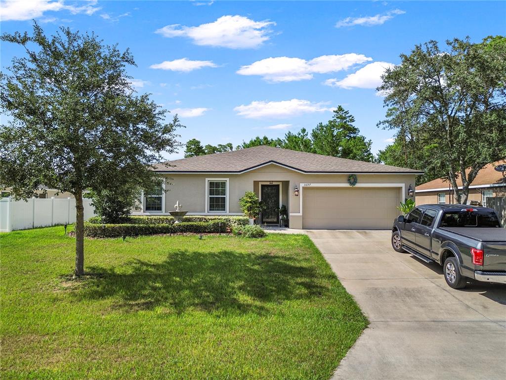 A single-story house with a beige exterior, a two-car garage, and a concrete driveway — 3697 SW 128TH PLACE, OCALA, FL