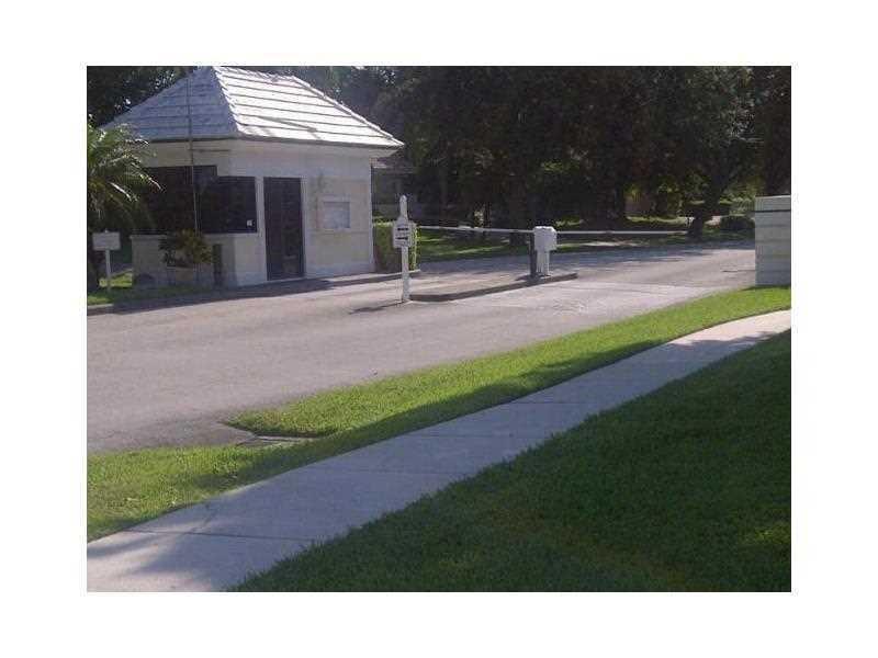 A gated entrance features a small guardhouse, a paved driveway, and a security barrier arm — 3650 Whitehall Drive # 403, West Palm Beach FL 33401, WEST PALM BEACH, FL