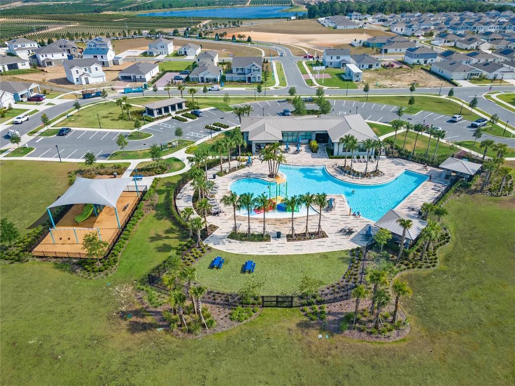 An aerial view shows a community swimming pool, playground, and clubhouse surrounded by suburban houses — 1774 PERCH HAMMOCK LOOP, GROVELAND, FL