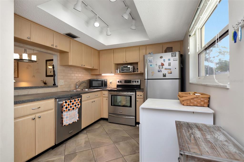 A kitchen features light wood cabinets, stainless steel appliances, a tiled floor, and recessed lighting — 1024 DE SOTO DRIVE, DUNEDIN, FL