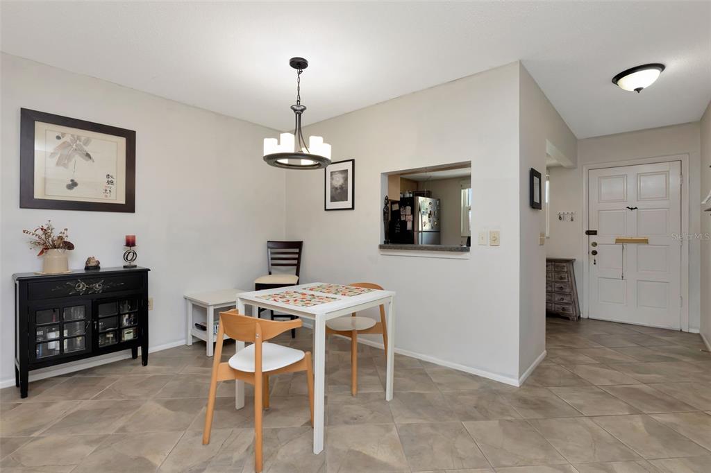 A dining area features a white table, three chairs, a black cabinet, and tile flooring — 1024 DE SOTO DRIVE, DUNEDIN, FL