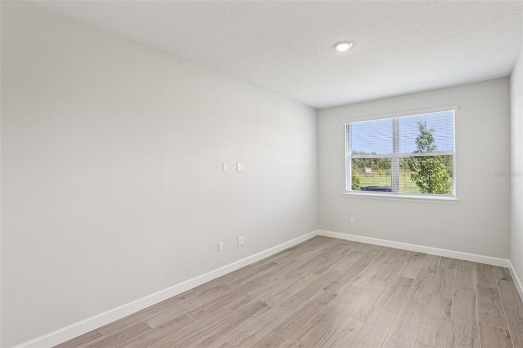 An empty room features light gray walls, wood-look tile flooring, and a window with blinds — 7558 DEER VALLEY CIRCLE, TAMPA, FL