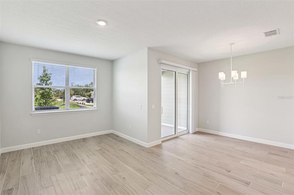 A bright dining area features light wood-look tile flooring, a chandelier, and sliding glass doors — 7558 DEER VALLEY CIRCLE, TAMPA, FL