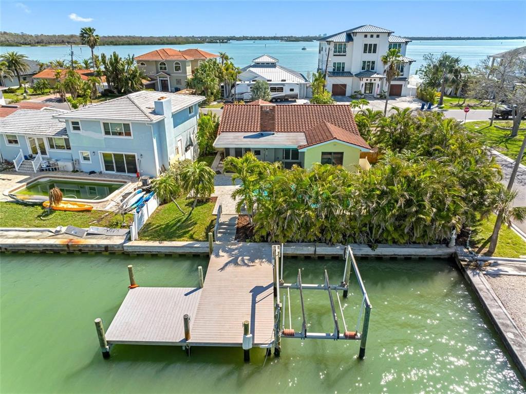 An aerial view shows a waterfront house with a private dock and boat lift — 562 JOHNS PASS AVENUE, MADEIRA BEACH, FL