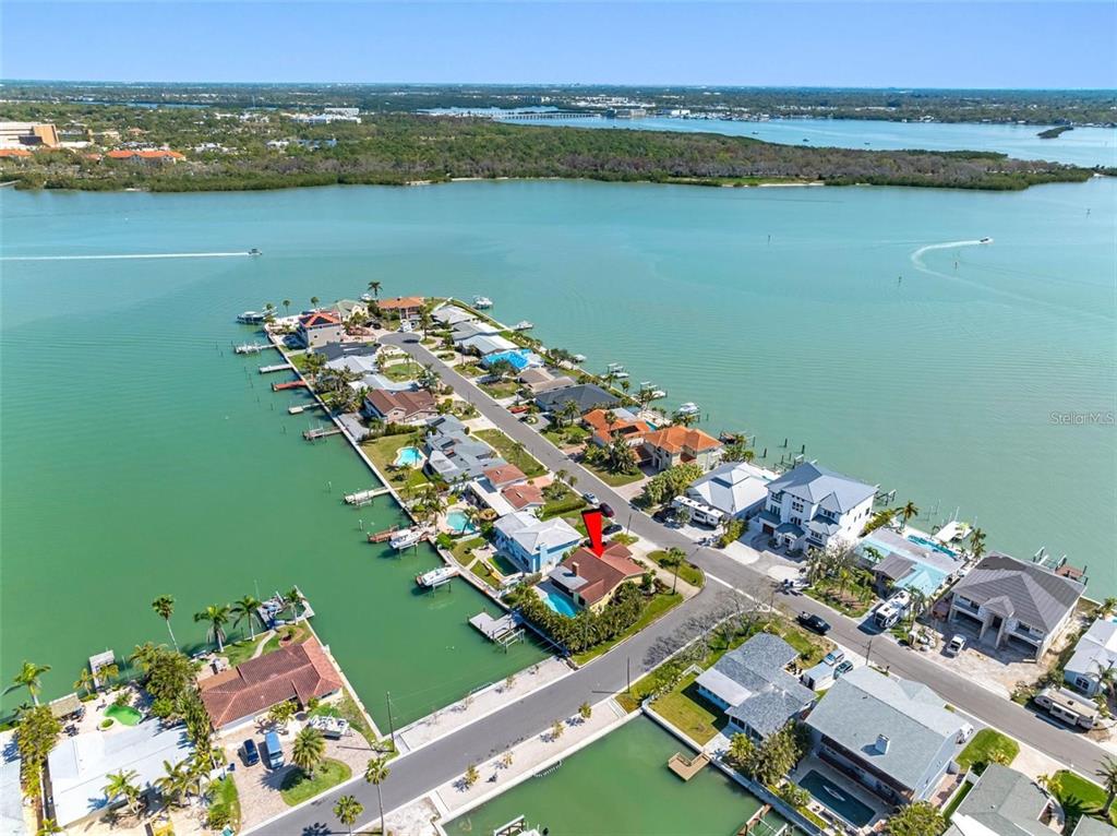 An aerial view shows a waterfront house with a pool on a residential peninsula — 562 JOHNS PASS AVENUE, MADEIRA BEACH, FL
