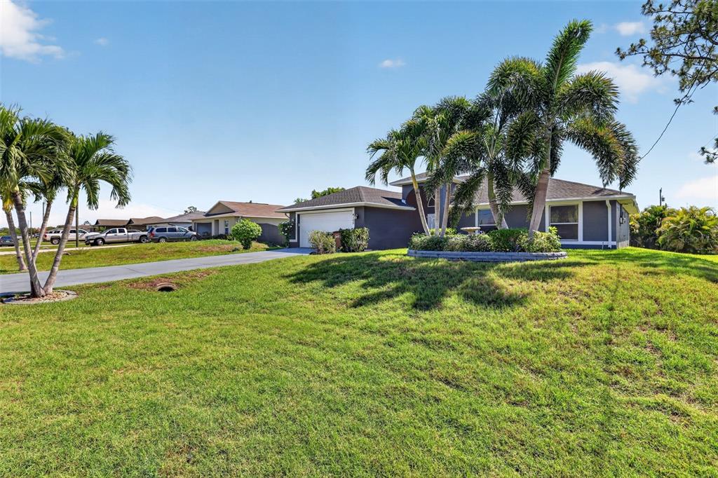 A single-story house with a driveway and palm trees sits on a grassy lawn — 4105 NE 20TH PLACE, CAPE CORAL, FL