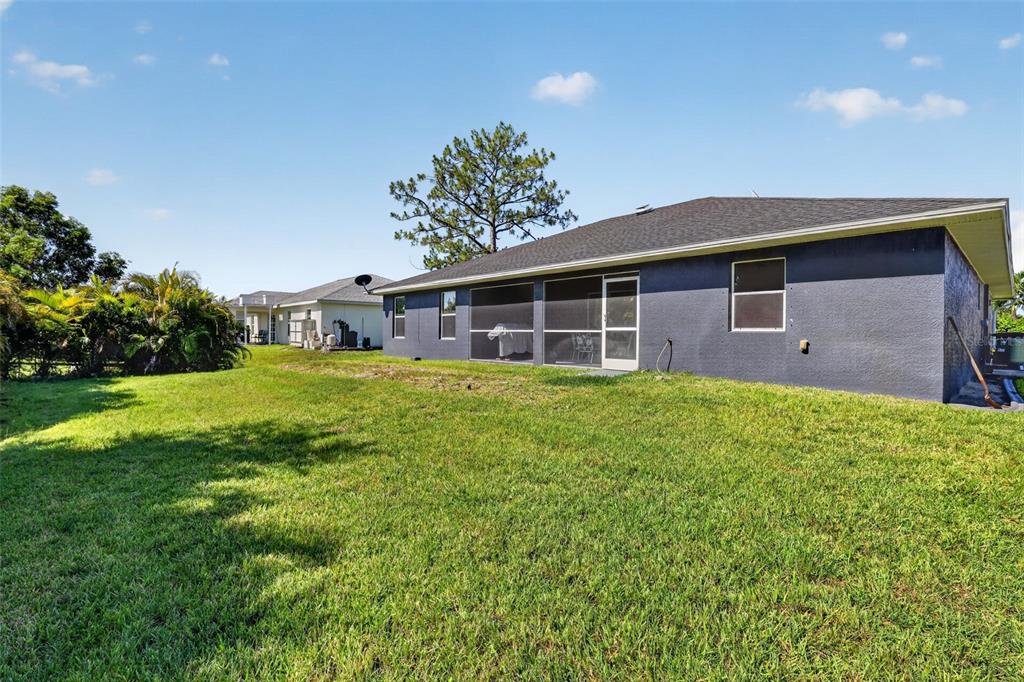 The exterior of a dark gray house with a screened-in lanai and a grassy backyard — 4105 NE 20TH PLACE, CAPE CORAL, FL