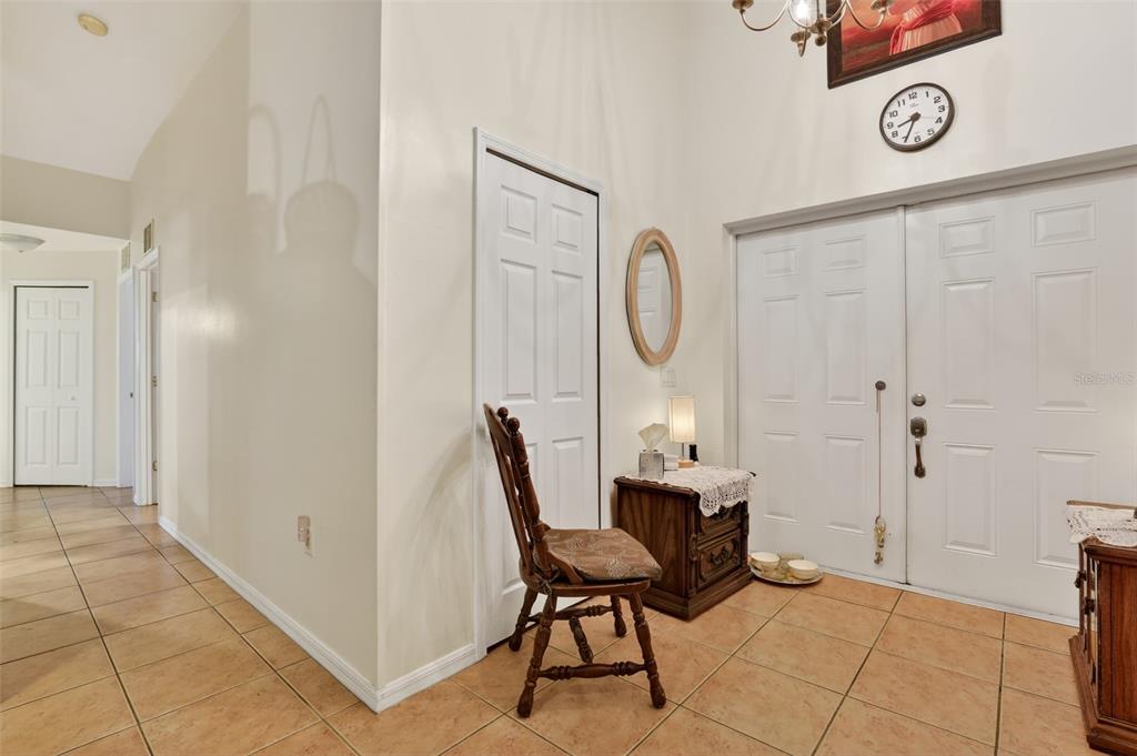 An entryway features tiled floors, a wooden chair, a small side table, and double doors — 4105 NE 20TH PLACE, CAPE CORAL, FL