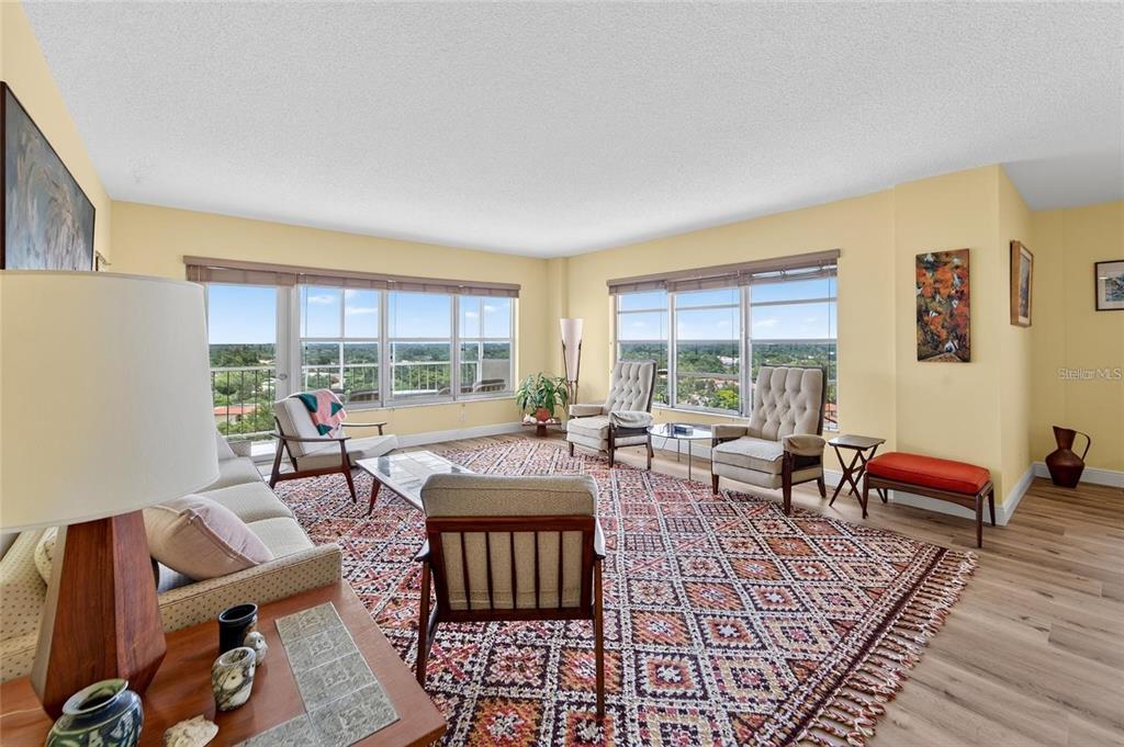 A living room features light yellow walls, a patterned area rug, and large windows with views — 10777 W SAMPLE ROAD UNIT 1212, CORAL SPRINGS, FL