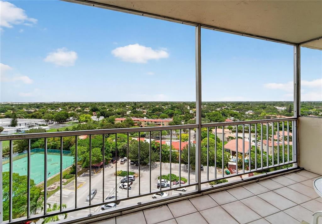 A high-rise balcony with a tiled floor overlooks a parking lot, tennis court, and neighborhood — 10777 W SAMPLE ROAD UNIT 1212, CORAL SPRINGS, FL