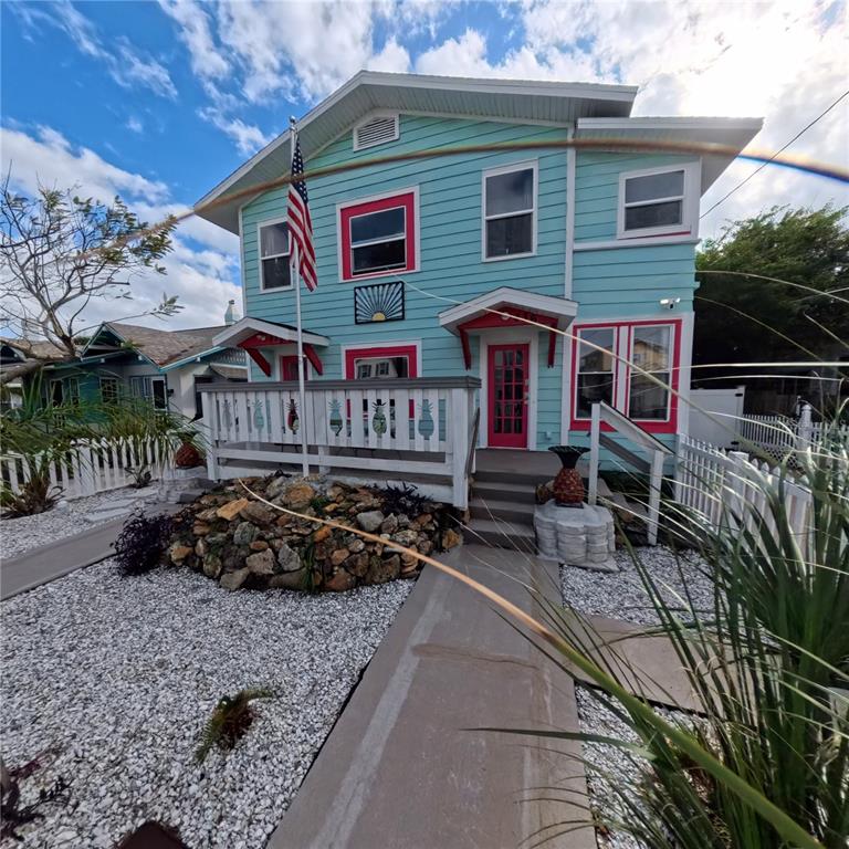 A two-story light blue house features a front porch, a rock garden, and white fencing — 434 VERMONT AVENUE, DAYTONA BEACH, FL