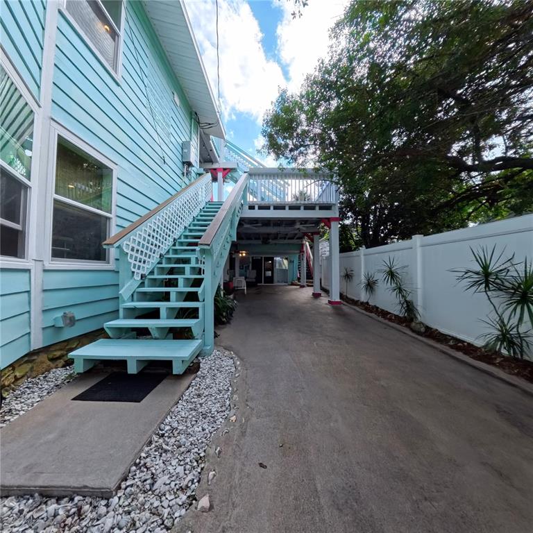 A light blue house features an exterior staircase leading to an elevated deck and driveway — 434 VERMONT AVENUE, DAYTONA BEACH, FL