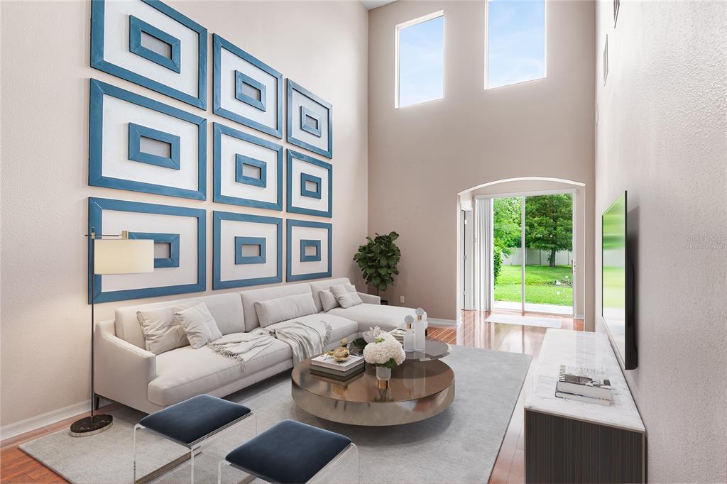 A living room with high ceilings, a large sectional sofa, and blue-framed wall art — 10077 MOORSHIRE CIRCLE, ORLANDO, FL