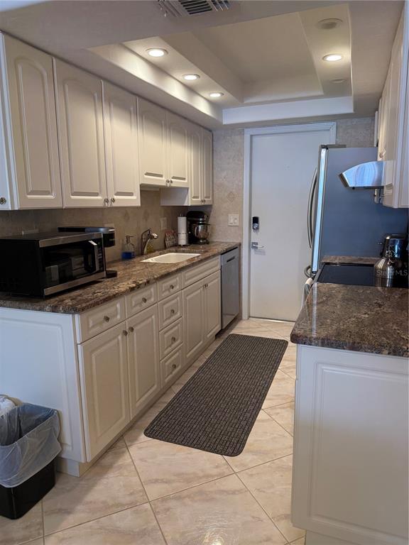 A kitchen features white cabinets, granite countertops, stainless steel appliances, and light-colored tile flooring — 3806 GULF OF MEXICO DRIVE UNIT C212, LONGBOAT KEY, FL