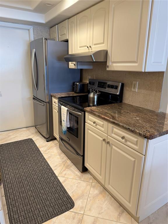 A kitchen features cream cabinets, granite countertops, stainless steel appliances, and light-colored tile flooring — 3806 GULF OF MEXICO DRIVE UNIT C212, LONGBOAT KEY, FL