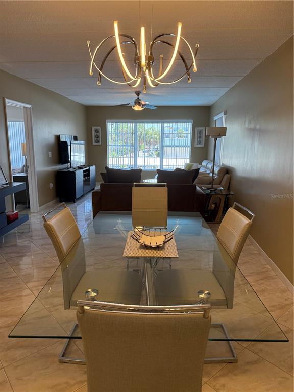 A dining area with a glass table and modern chandelier opens into a living room — 3806 GULF OF MEXICO DRIVE UNIT C212, LONGBOAT KEY, FL