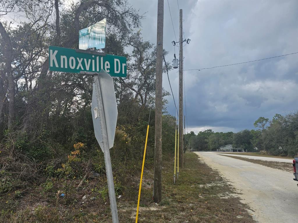A street sign for Knoxville Drive stands beside a dirt road and utility poles — 7131 KNOXVILLE DRIVE, WEBSTER, FL