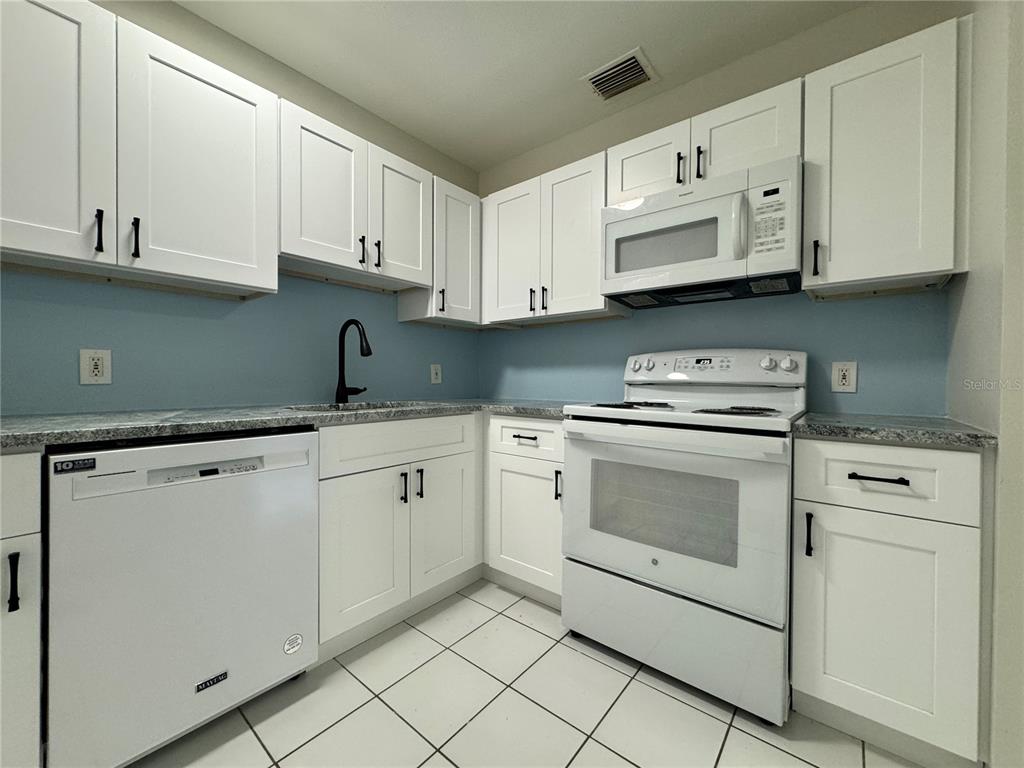 A kitchen with white cabinets, a white dishwasher, a white stove, and light blue walls — 260 20TH AVENUE S, ST PETERSBURG, FL