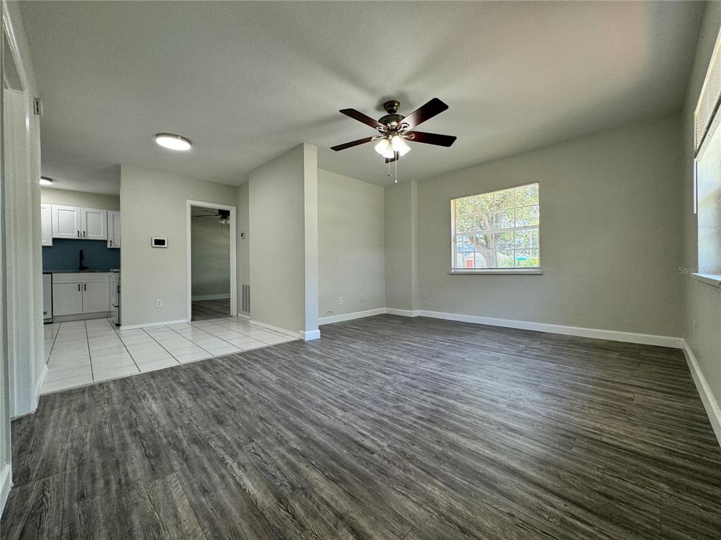 An open-concept living room with wood-look flooring connects to a tiled kitchen area — 260 20TH AVENUE S, ST PETERSBURG, FL