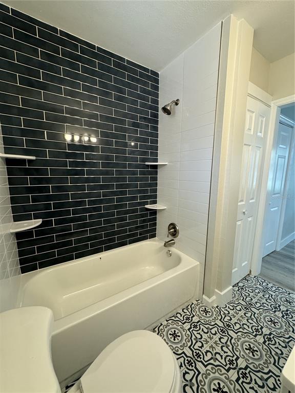 A bathroom features a white bathtub, dark blue subway tile, and patterned floor tiles — 260 20TH AVENUE S, ST PETERSBURG, FL