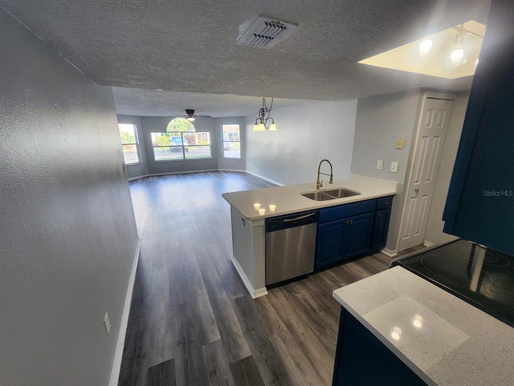 A kitchen with blue cabinets and white countertops overlooks a living area with wood flooring — 2745 N POINCIANA BOULEVARD UNIT 63, KISSIMMEE, FL