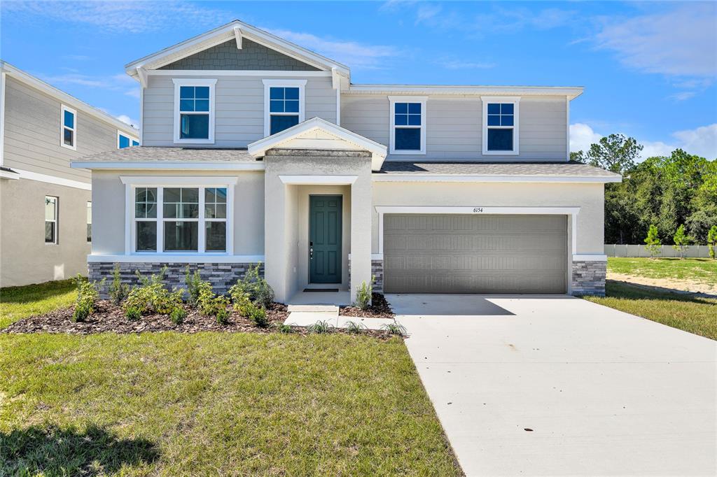 A two-story suburban house features a gray garage, a dark front door, and stone accents — 6154 SW 64TH TERRACE, OCALA, FL