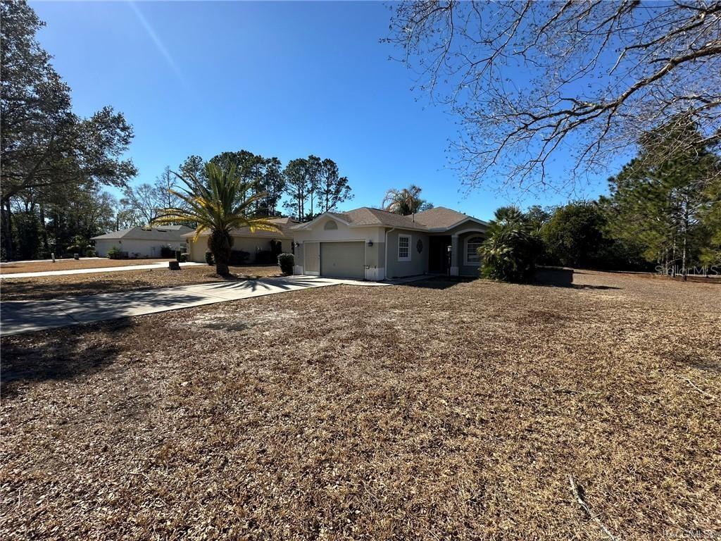 A single-story house with a beige exterior, a two-car garage, and a large, dry lawn — 2394 N BRENTWOOD CIRCLE, LECANTO, FL