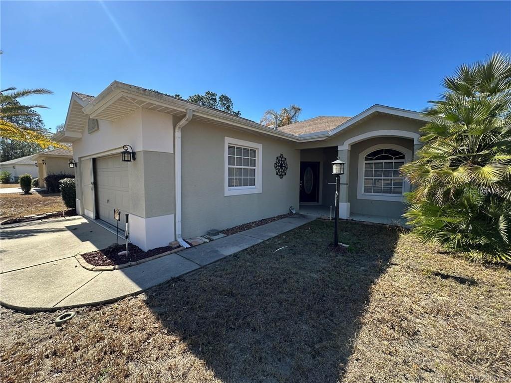 A single-story house with a beige stucco exterior, a garage, and a front walkway — 2394 N BRENTWOOD CIRCLE, LECANTO, FL