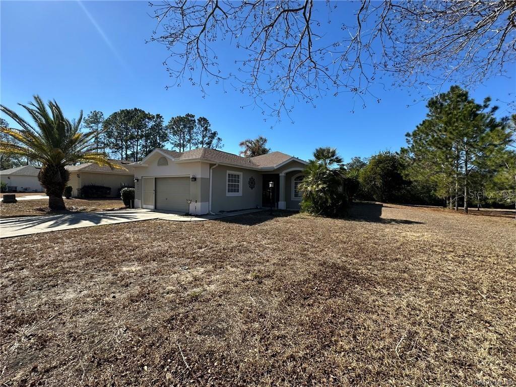 A single-story house with a beige exterior, a two-car garage, and a large dry lawn — 2394 N BRENTWOOD CIRCLE, LECANTO, FL
