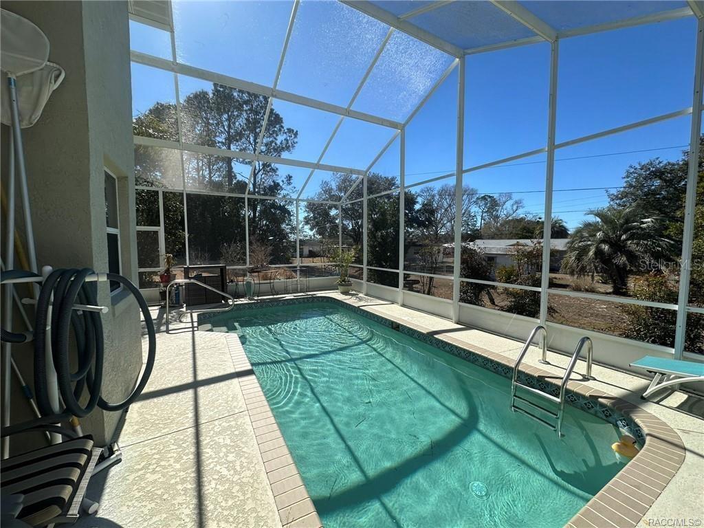 A screened-in swimming pool with a concrete deck and metal pool ladder — 2394 N BRENTWOOD CIRCLE, LECANTO, FL