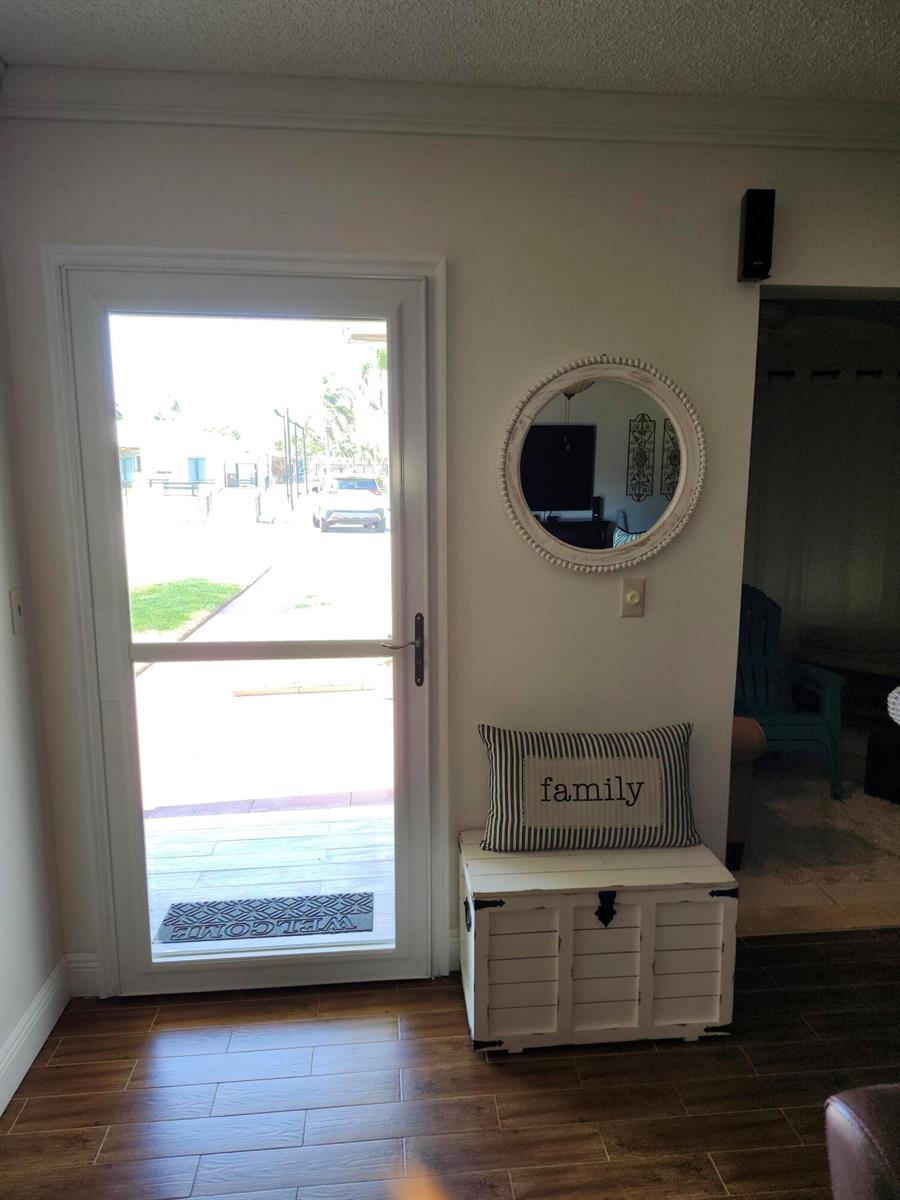 An entryway features a white door, a round mirror, and a white storage chest — 101 Country Lane, Boynton Beach FL 33435, BOYNTON BEACH, FL