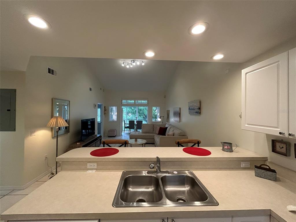 A kitchen sink overlooks an open-concept living area with a sectional sofa and dining space — 3605 54TH DRIVE W UNIT 203, BRADENTON, FL