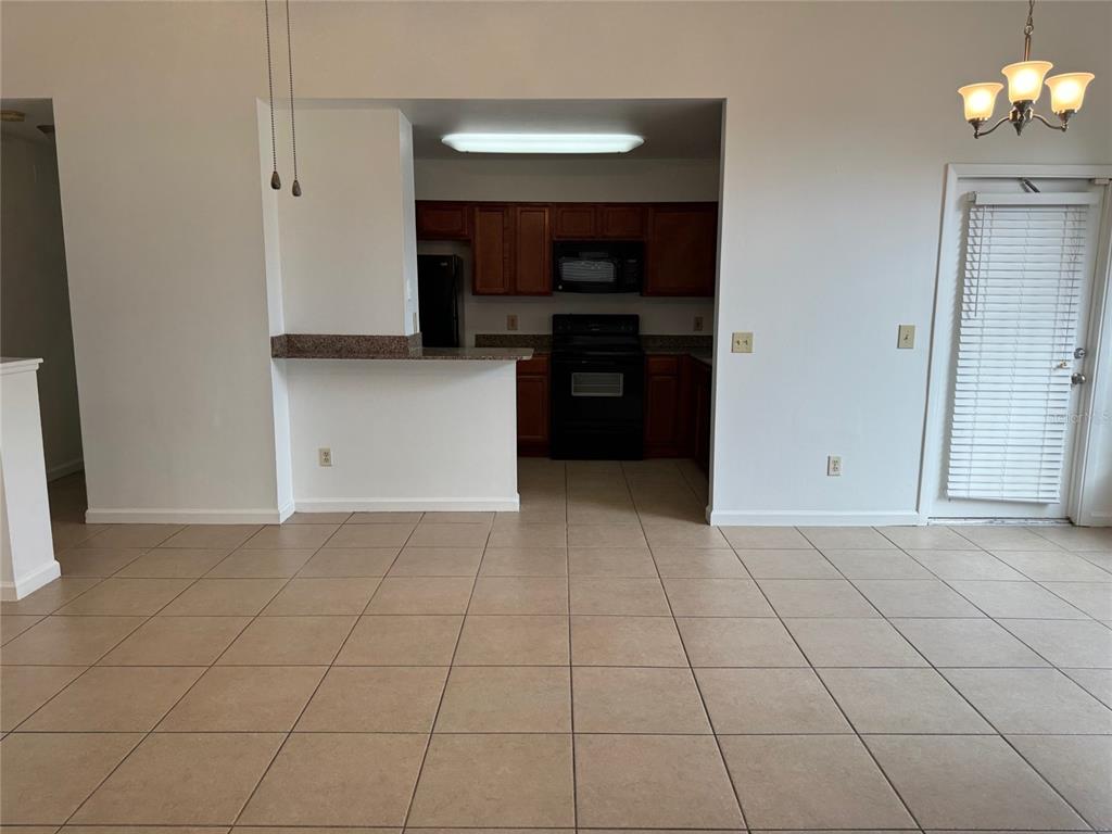 A kitchen with dark wood cabinets and black appliances overlooks a tiled dining area — 5436 E MICHIGAN STREET UNIT 5436-8, ORLANDO, FL
