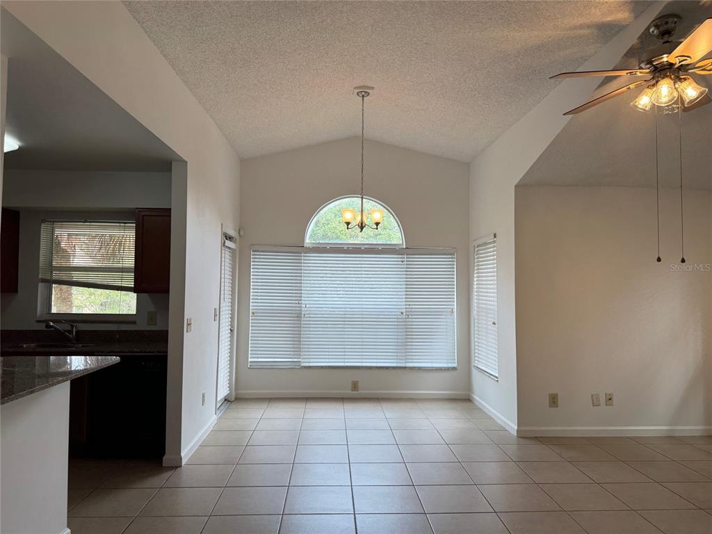 A dining area with tile floors, a vaulted ceiling, and a large arched window — 5436 E MICHIGAN STREET UNIT 5436-8, ORLANDO, FL