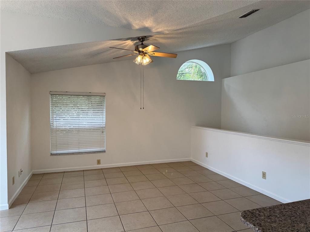 An empty room with beige tile flooring, a vaulted ceiling, and a ceiling fan — 5436 E MICHIGAN STREET UNIT 5436-8, ORLANDO, FL