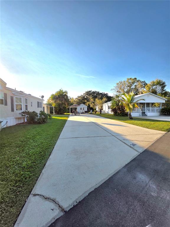 A concrete driveway leads between two manufactured homes toward a small shed and palm tree — 26 W APPALOOSA TRAIL, RIVER RANCH, FL