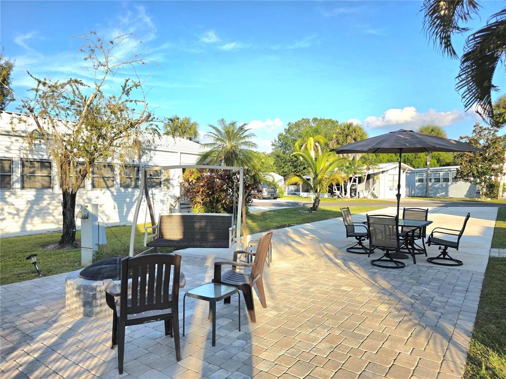 A paved patio features a fire pit, a porch swing, and a dining set with umbrella — 26 W APPALOOSA TRAIL, RIVER RANCH, FL