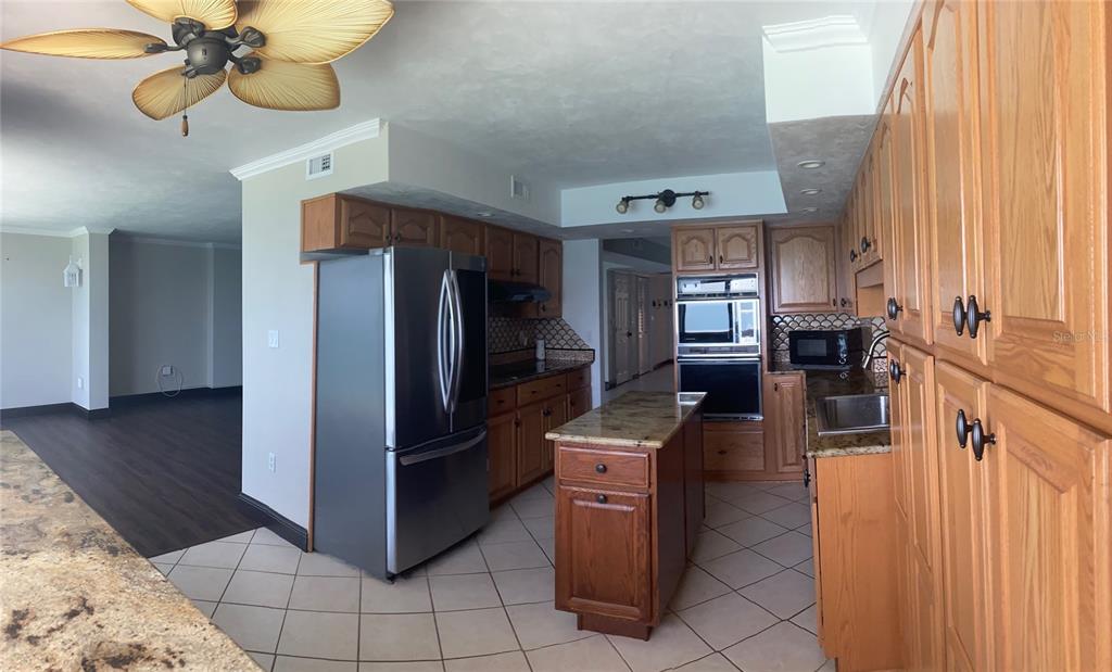 A kitchen features wood cabinets, granite countertops, a stainless steel refrigerator, and a center island — 3003 S ATLANTIC AVENUE UNIT 21B4, DAYTONA BEACH SHORES, FL