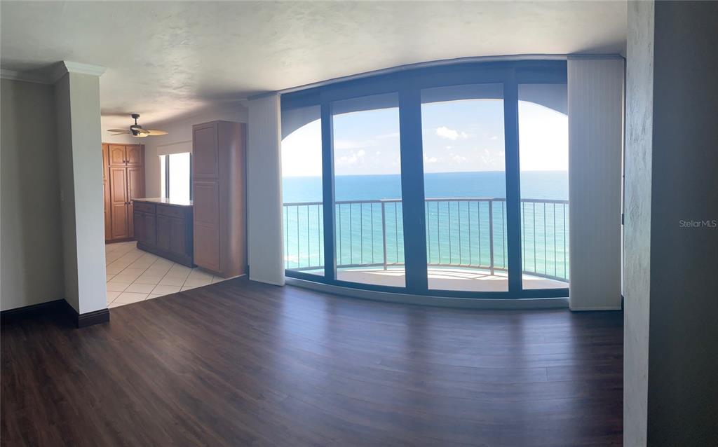 An open living area with dark wood floors leads to a balcony overlooking the ocean — 3003 S ATLANTIC AVENUE UNIT 21B4, DAYTONA BEACH SHORES, FL