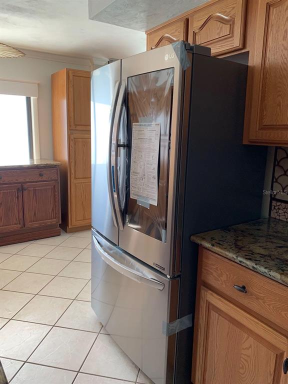 A stainless steel LG refrigerator stands in a kitchen with oak cabinets and tile flooring — 3003 S ATLANTIC AVENUE UNIT 21B4, DAYTONA BEACH SHORES, FL