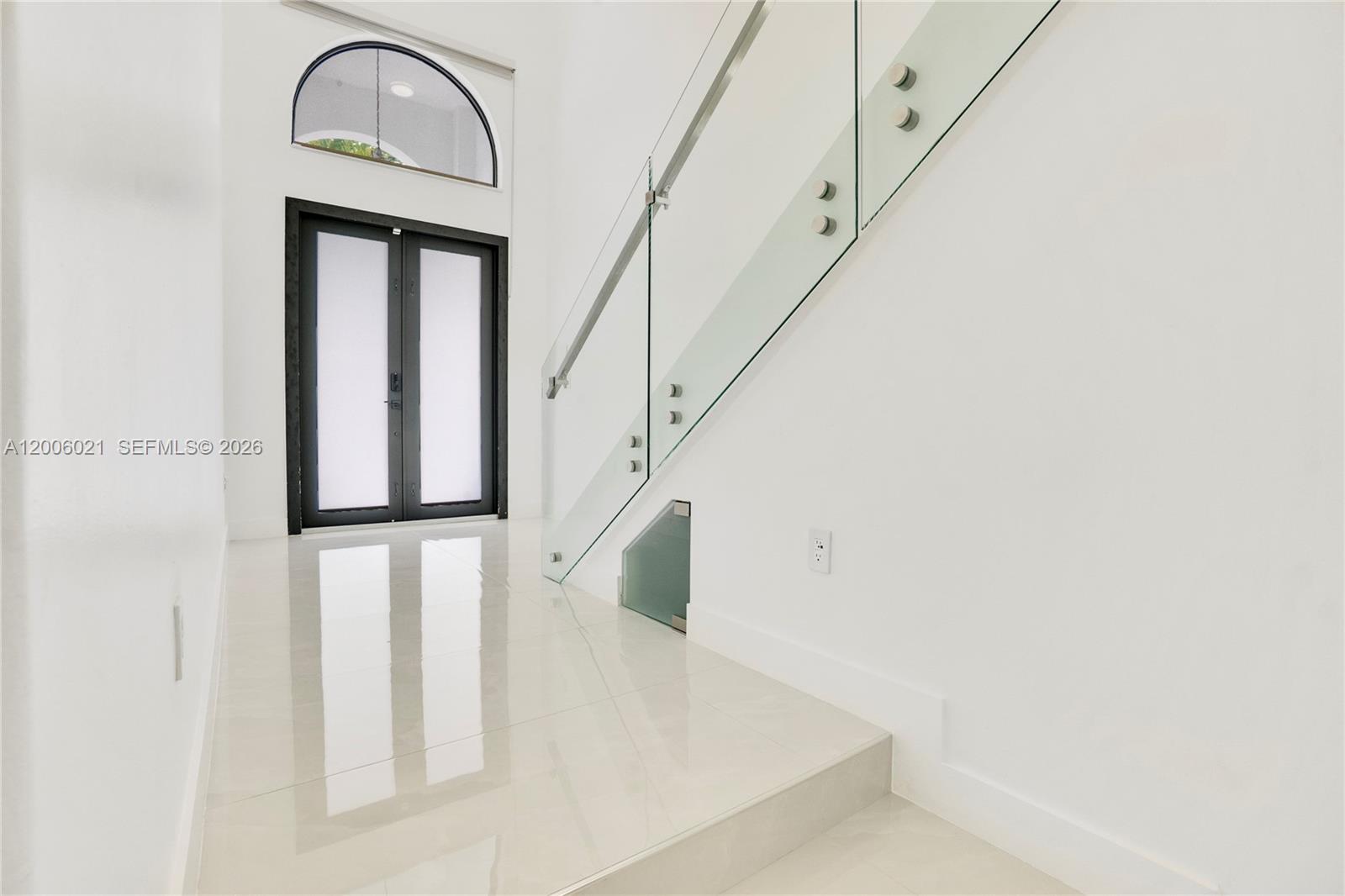 A modern entryway features white tile floors, a glass staircase railing, and a double door — 16621 SW 58th Ter, Miami FL 33193, MIAMI, FL