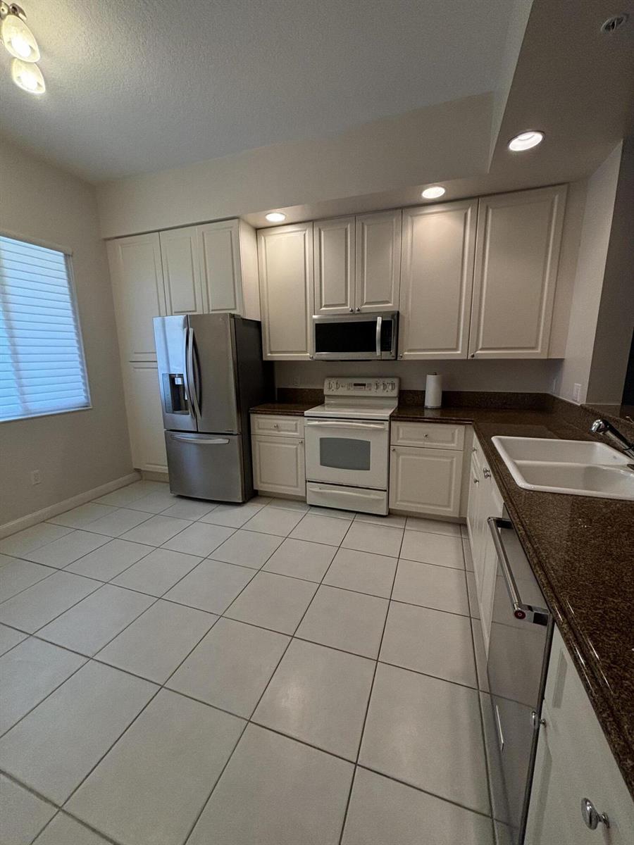 A kitchen features white cabinets, stainless steel appliances, brown countertops, and light-colored tile flooring — 10 E Harbour Isle Dr Drive E # 302, Fort Pierce FL 34949, FORT PIERCE, FL