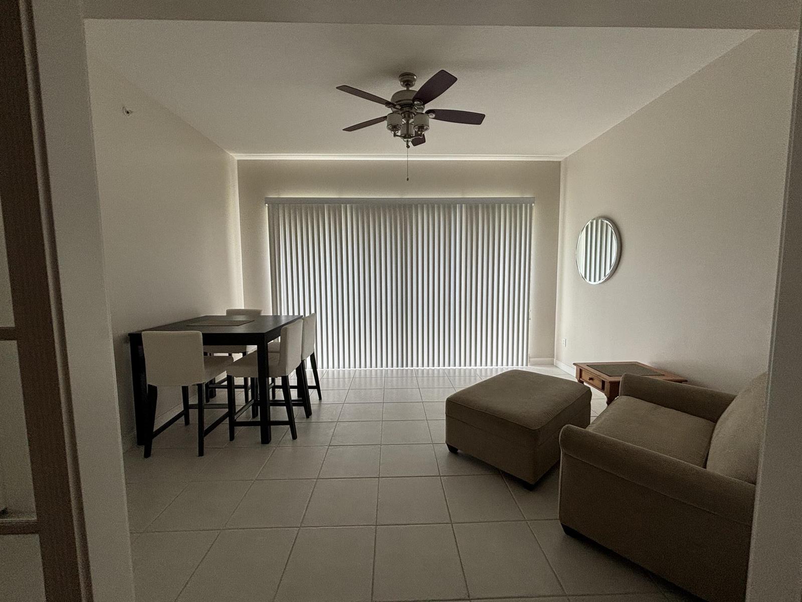 A dining and living area features tile flooring, a ceiling fan, and vertical window blinds — 10 E Harbour Isle Dr Drive E # 302, Fort Pierce FL 34949, FORT PIERCE, FL