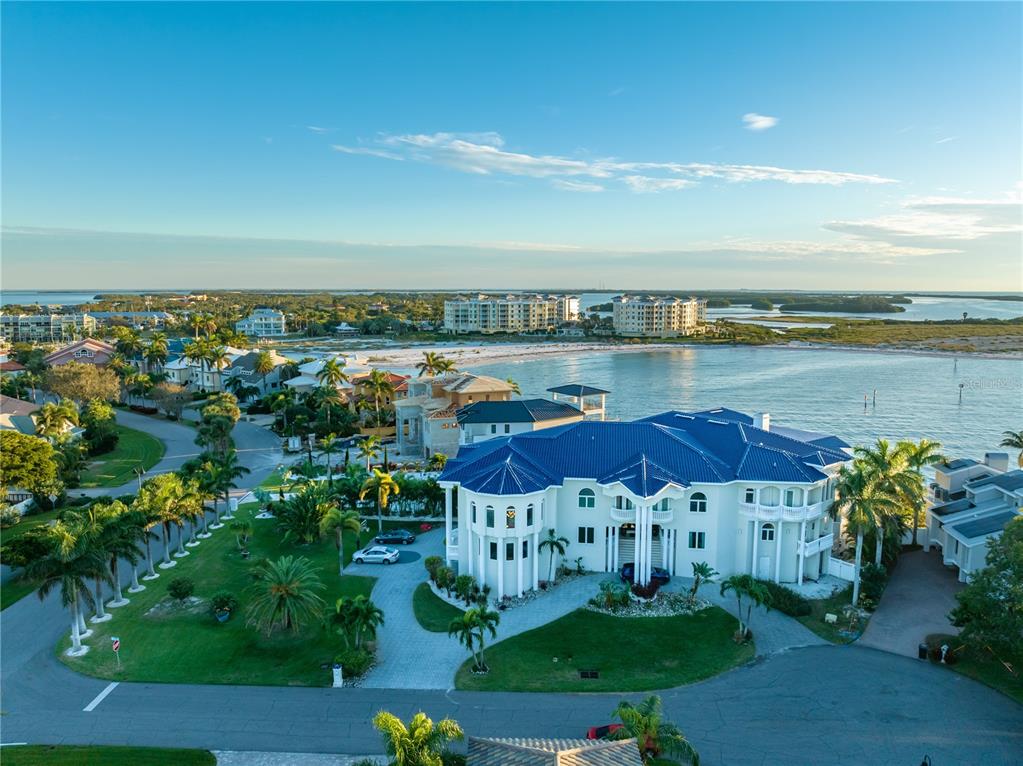 An aerial view of a large white waterfront mansion with a blue metal roof — 774 NINA DRIVE, TIERRA VERDE, FL
